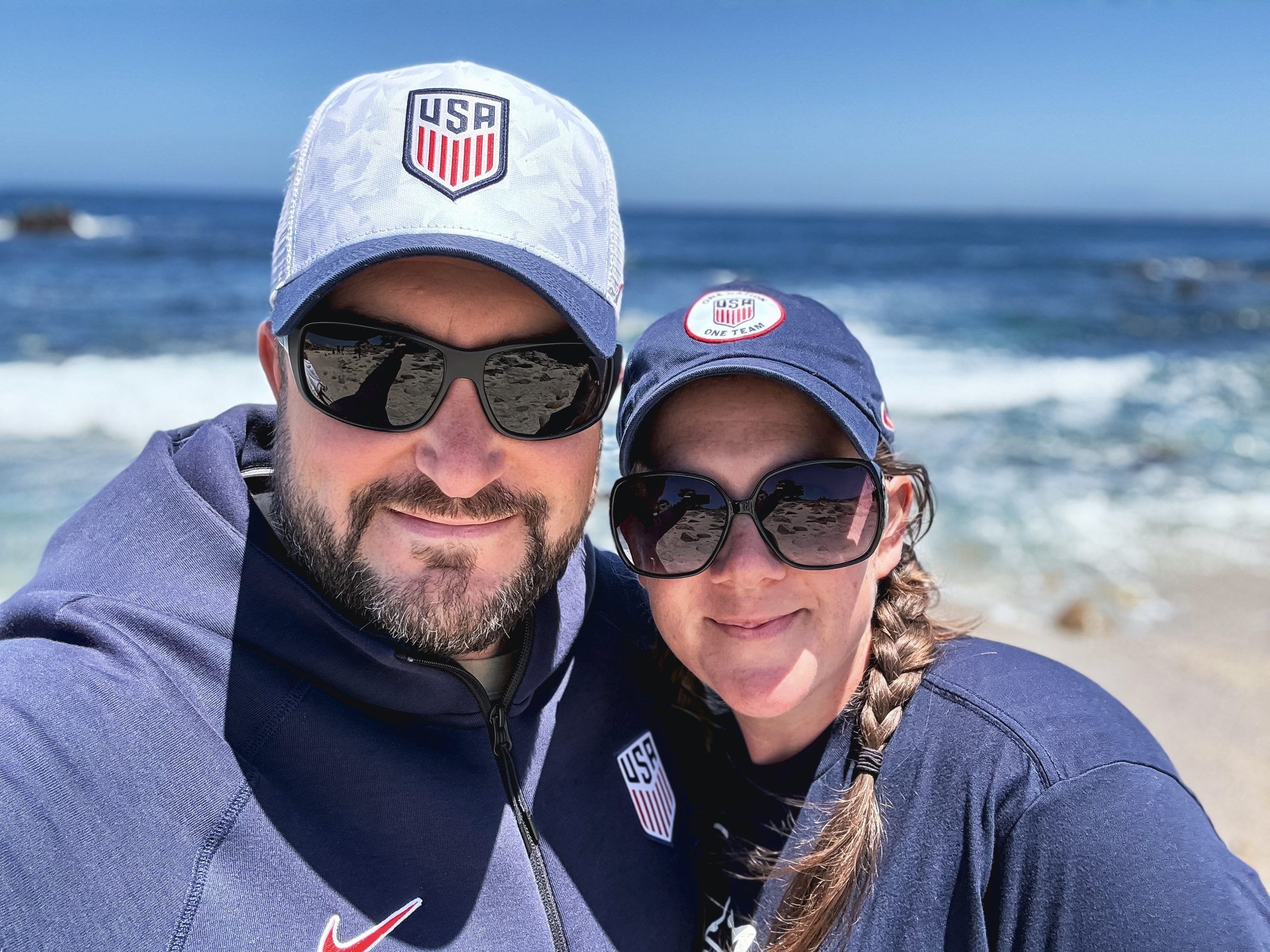 Joshua Brown and Laura taking a selfie on a beach with waves behind them.