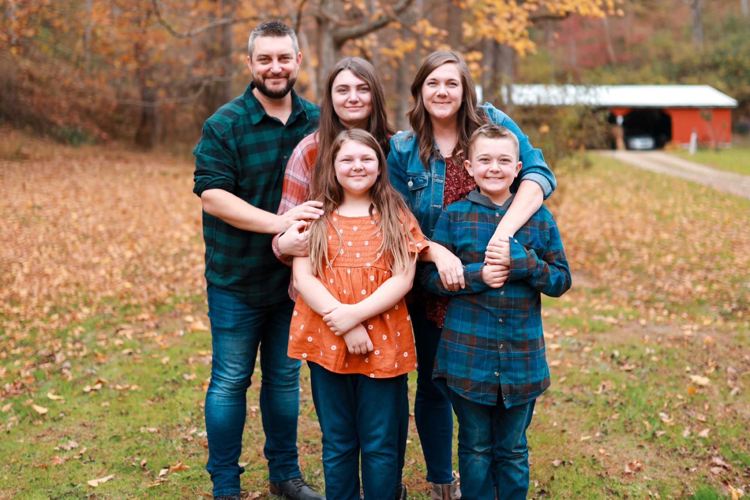Joshua Brown with Laura and their three kids standing outdoors in fall leaves.