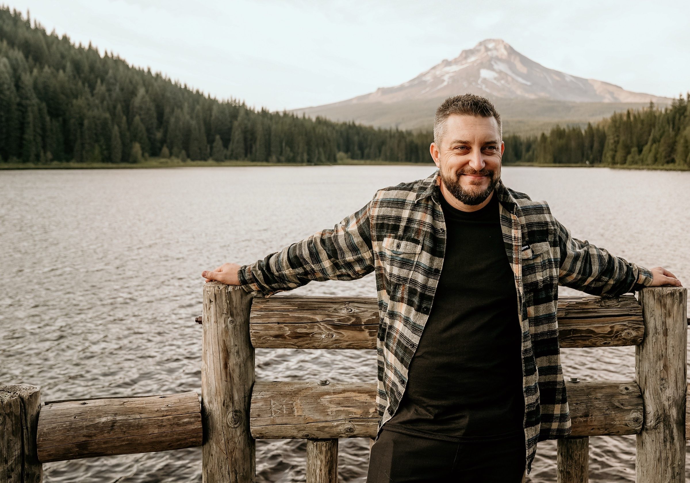 Joshua Brown leaning on a wooden rail at a lake with Mount Hood behind him.